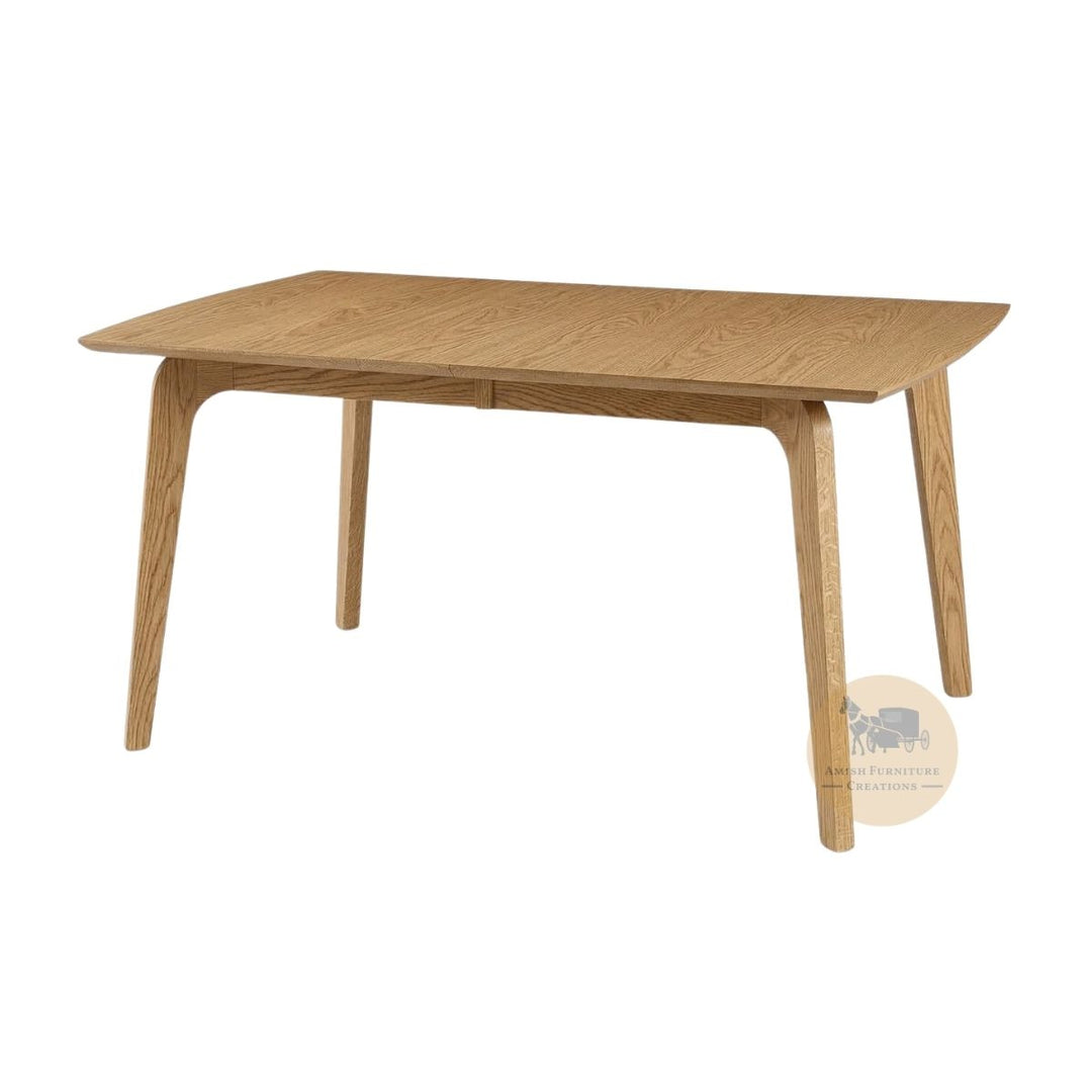 A mid-century modern wooden dining table with a light oak finish, featuring tapered legs and a rectangular top with curved ends, shown on a plain white background with an Amish Furniture Creations logo in the lower right .