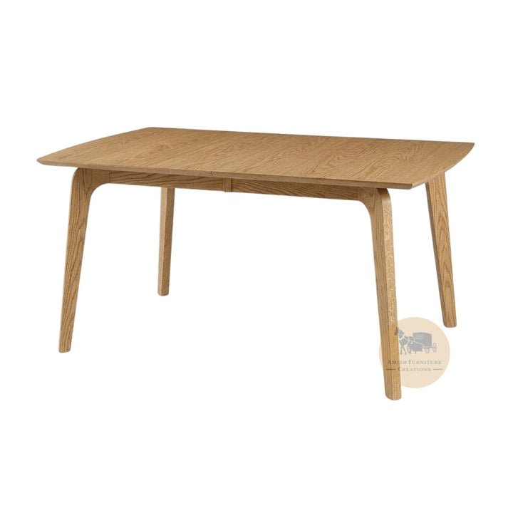 A mid-century modern wooden dining table with a light oak finish, featuring tapered legs and a rectangular top with curved ends, shown on a plain white background with an Amish Furniture Creations logo in the lower right .