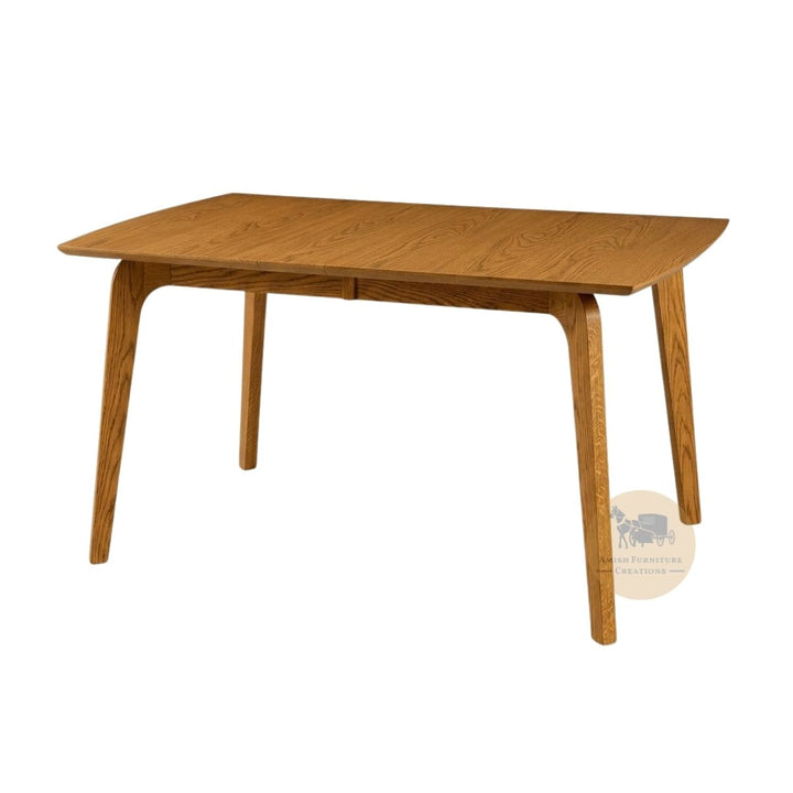 A mid-century modern wooden dining table with a medium brown finish, featuring tapered legs and a rectangular top with curved ends, shown on a plain white background with an Amish Furniture Creations logo in the lower right .
