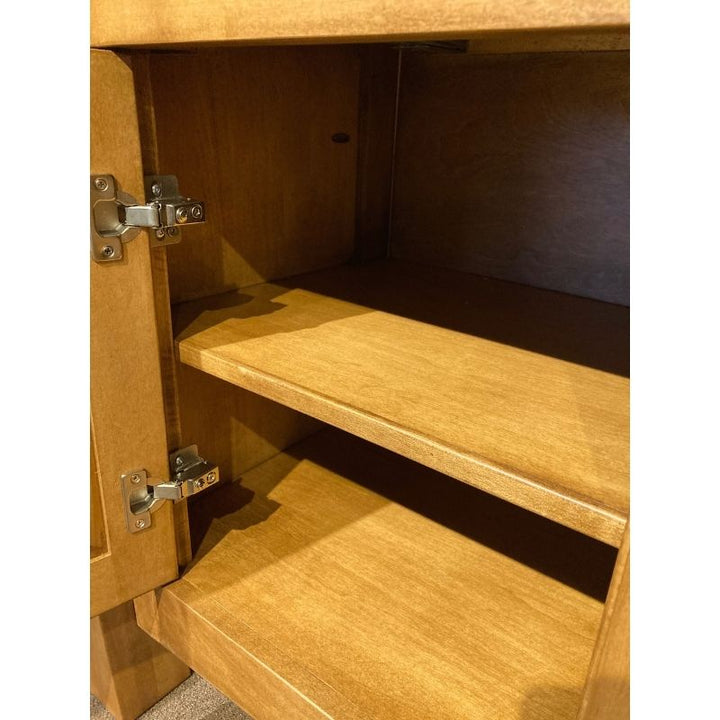 Close up view of the hard maple wood buffet base with an open door to show the fixed shelf - in a showroom setting - Amish Furniture Creations™