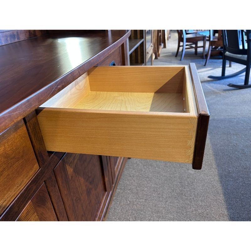 Close up view of one wood drawer open on the cherry wood buffet in a showroom setting - Amish Furniture Creations™